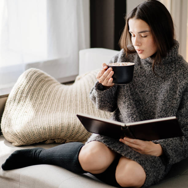 istock Woman drinking hot chocolate, reading a book. 1266720579
