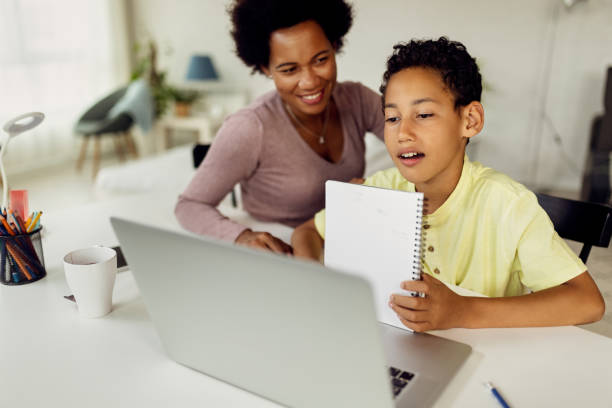 istock Black boy making video call over laptop while homeschooling with his mother. 1266722490