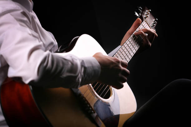 istock Young men playing the guitar with black background 1266722559