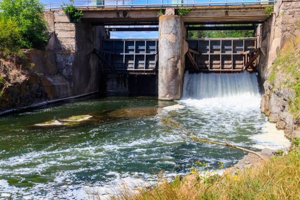 flowing water with water spray from the open sluice gates of a small dam - miniature weir imagens e fotografias de stock