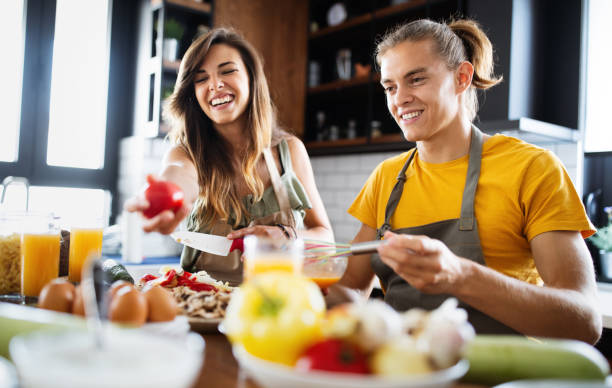 istock Beautiful couple is smiling while cooking together in the kitchen 1266729912