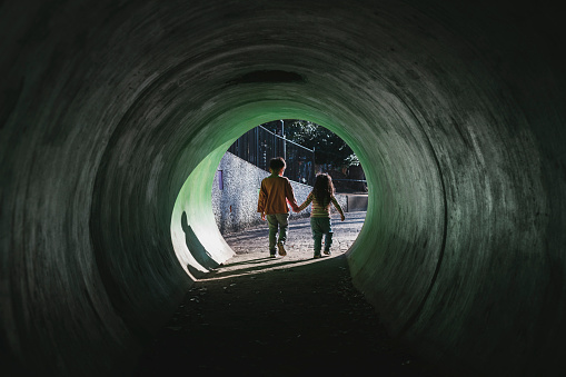 Asian brother and sister walking through tunnel in the park.