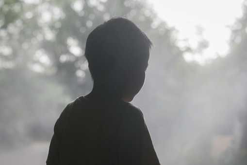 Asian boy walking through fog.