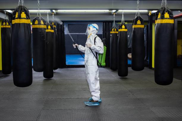 gym employee wearing ppe and disinfecting everything - protective suit fotos imagens e fotografias de stock