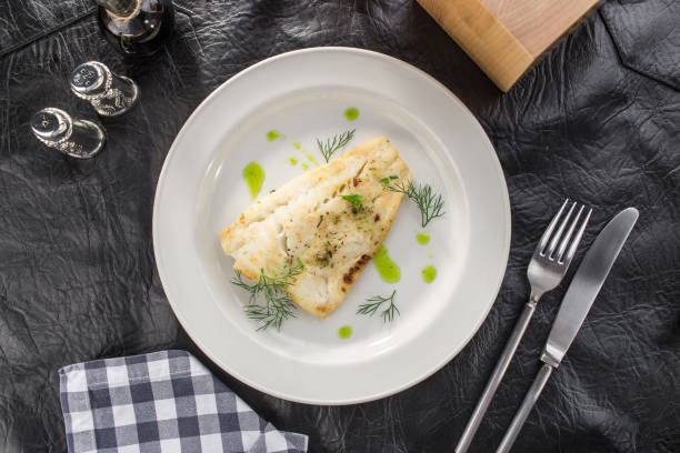 filé de peixe branco frito no prato branco com suco de tomate na mesa de couro preto - cod fillet fried prepared fish - fotografias e filmes do acervo