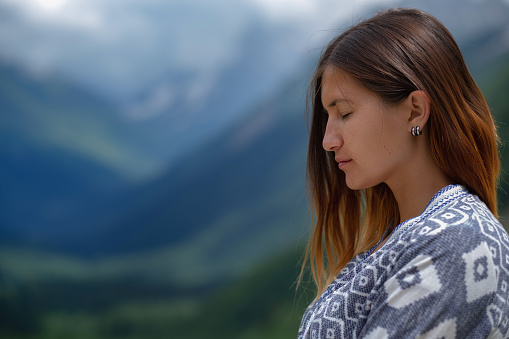 Stylish female hipster walking on top of mountains. Happy young woman exploring sunny mountains. Travel and wanderlust concept. Amazing atmospheric moment. North Caucasus, Dombai, Russia.