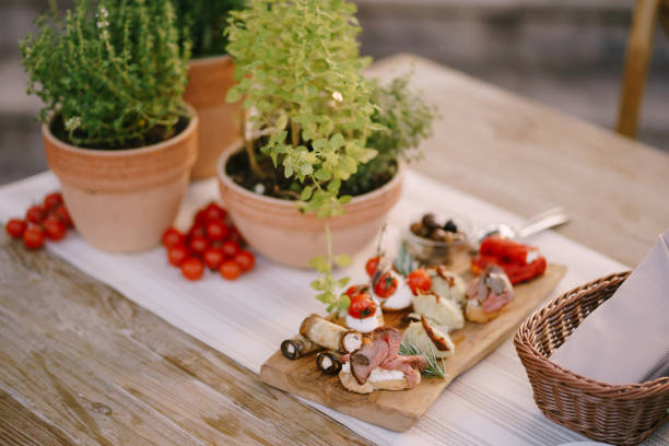 istock Red tomatoes on a table with a cutting board and flowers in pots. 1266739676
