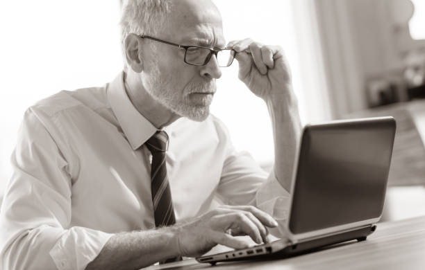 istock Mature businessman working on laptop, black and white 1266742390