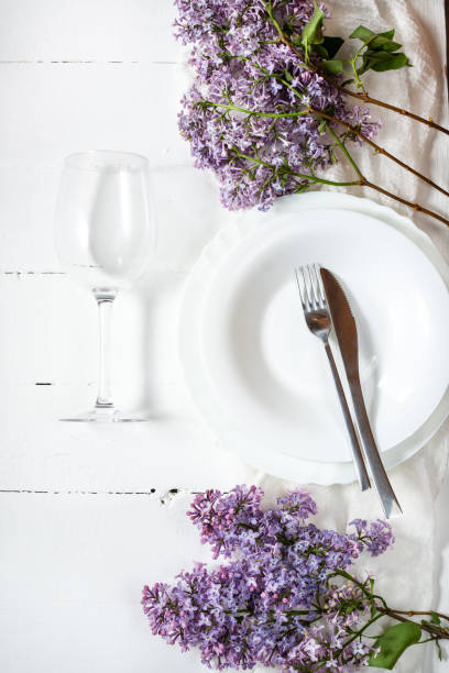 istock Spring floral table settings with spring flowers. Top view. Plates, wine glass and cutlery with decorative textile on white wooden background 1266743702