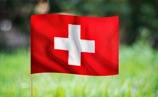 Swiss flag waving on a green background. Horizontal composition with copy space.