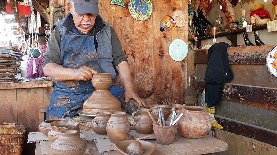 San Diego, California USA - 5 Jan 2020: Potter working in mexican Oldtown, raw clay on pottery wheel. Man's hands, ceramist in process of modeling handcrafted clayware. Craftsman creating ceramic.