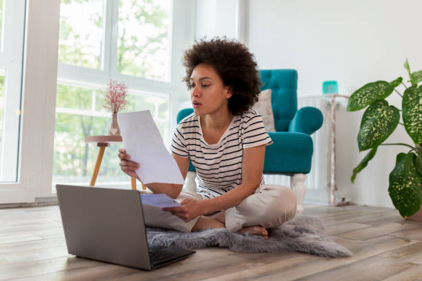 Woman paying bills online Beautiful woman sitting on the living room floor, calculating bank loan payout rates and paying household bills credit score photos stock pictures, royalty-free photos & images