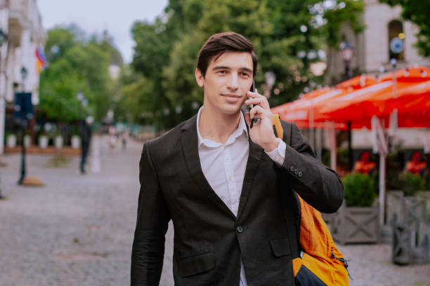 istock Man go on the street with backpack and speaks on smartphone 1266748155