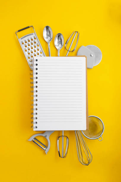 Kitchen utensils and open notebook for recipes, yellow background with space for text. Flat lay. Cooking concept.