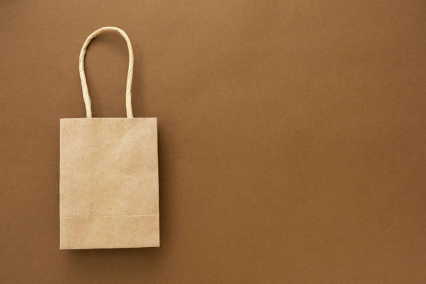 istock Craft brown paper shopping bag isolated on brown background, copy space. 1266749056
