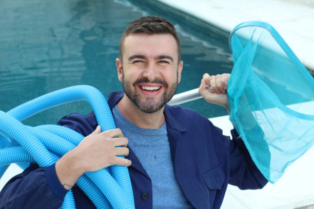 Hotel employee cleaning swimming pool stock photo