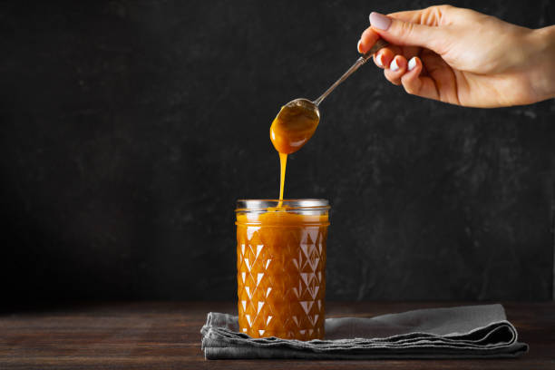 istock Liquid brown caramel in glass on dark background 1266755651