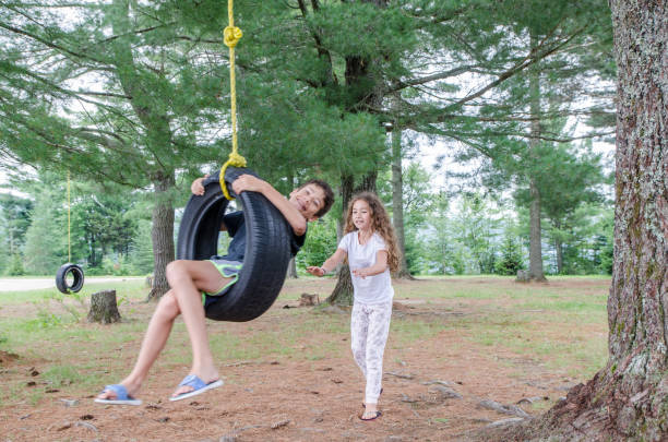 девушка помогает брату в качели - tire swing стоковые фото и изображения