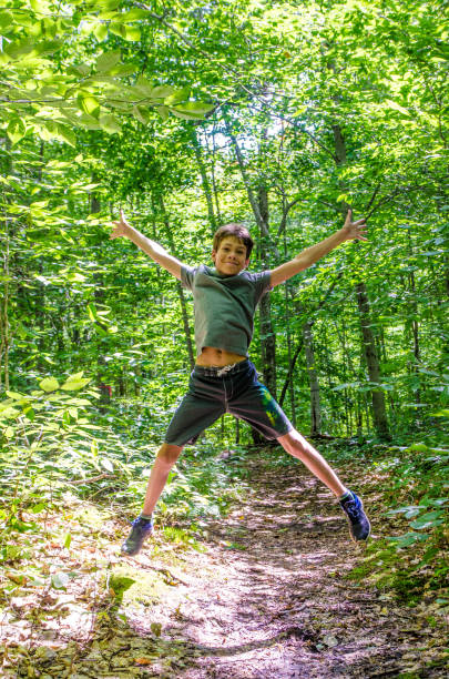 istock Boy jumping in the air in a footpath in forest 1266756615