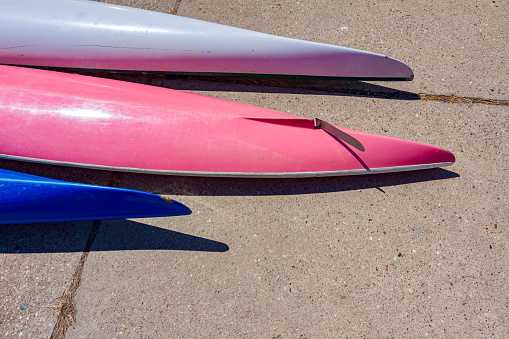 Row of upside down colorful kayaks placed on the concrete coastline beside the river.