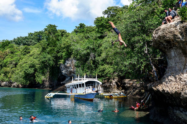 Man Jumping and flipping off a cliff to the sea Jumping off a cliff to the sea - Samal Island, Davao, Philippines 2019 davao city stock pictures, royalty-free photos & images