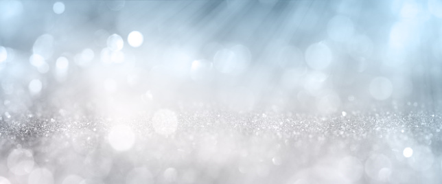 White bokeh effects on blue and silver glittering abstract background with rays of light. Background for wedding and christmas. Space for design and text.