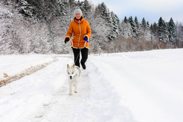 istock young woman runner training in winter park with husky dog 1266761152