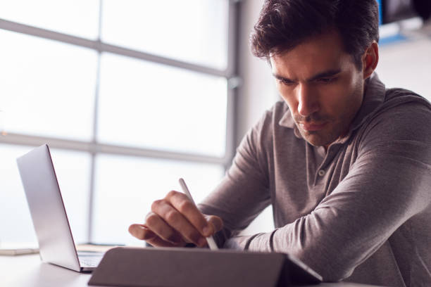istock Businessman Working From Home Drawing On Digital Tablet Using Stylus Pen 1266761954
