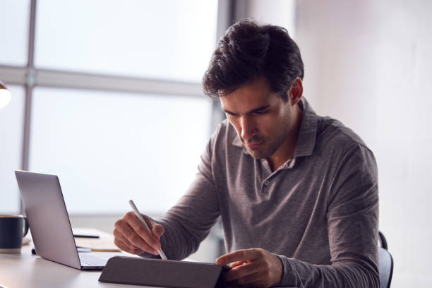istock Businessman Working From Home Drawing On Digital Tablet Using Stylus Pen 1266762045
