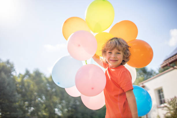 外にカラフルな風船を持つ4歳の男の子 - sun sky child balloon ストックフォトと画像