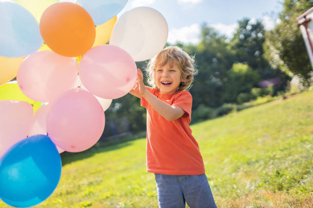 istock 4 years old boy with colorful balloons outside 1266763907