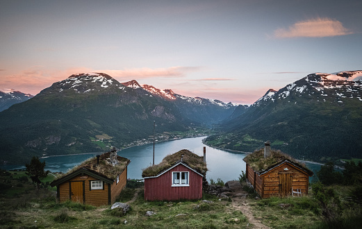 Three log cabins in front of fjord and sunset by Loen in Norway.