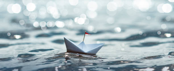 istock Paper Boat sailing on sunny Sea 1266765168