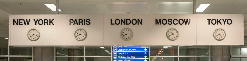 five white international clock with different time zone hanging on banner in airport station front view