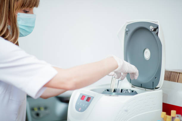 istock Woman in protective face mask and gloves putting tubes in analyzer 1266765476