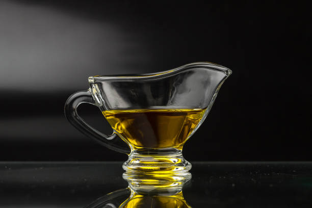 olivenöl in einem glas soße boot. pflanzenöl auf schwarzem hintergrund. - olive oil pouring antioxidant liquid stock-fotos und bilder