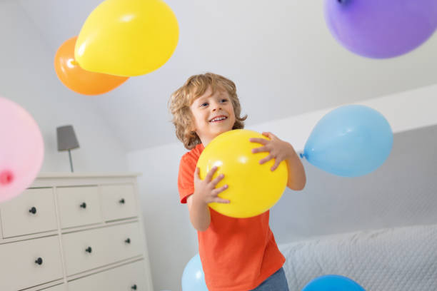 istock 4 years old boy with colorful balloons indoors 1266770131