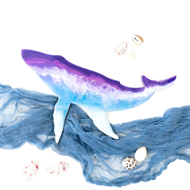 istock Resin art whale with fabric waves and sea shells on white background. Flat lay, top view 1266772327