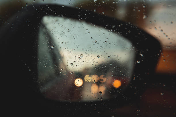 istock Rear view mirror seen through rain drops on the car window. 1266773628