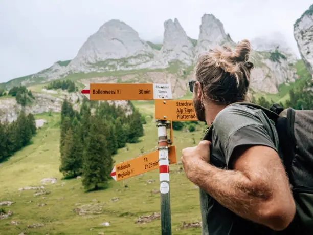 View of man hiking on mountain trail looking at spectacular view in Appenzellerland Canton, Switzerland