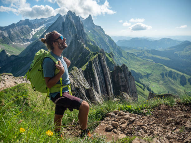 View of man hiking on mountain ridge looking at spectacular view in Appenzellerland Canton, Switzerland