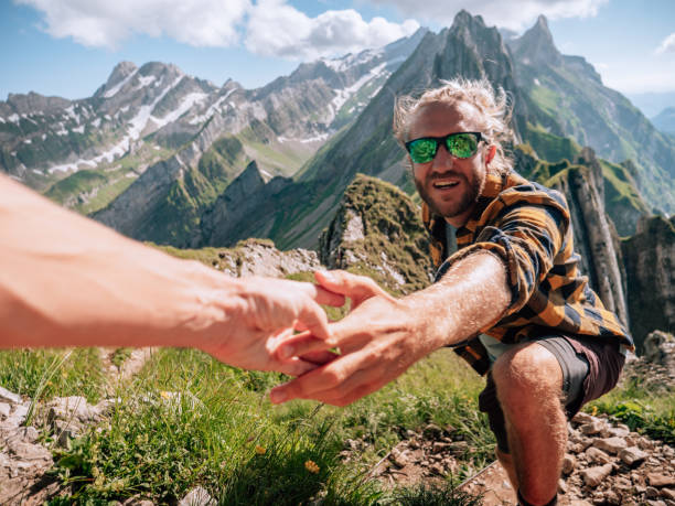 istock Hiker helping teammate to climb rock on mountain ridge 1266778276