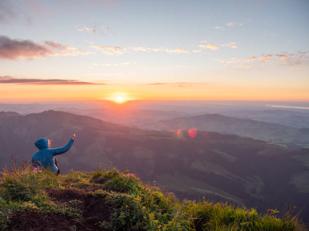 istock Woman photographing sunset from mountain peak using mobile phone 1266778712