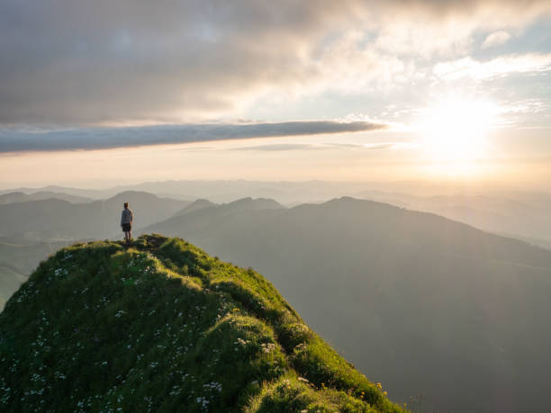 istock Distant man standing on top of mountain overlooking ridge at sunset 1266778742