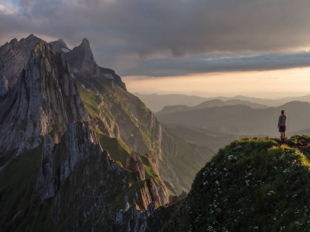 istock Distant man standing on top of mountain overlooking ridge at sunset 1266778756