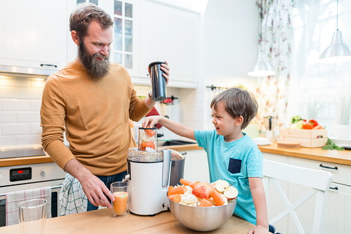 Father and son making fresh juice from fruits and vegetables