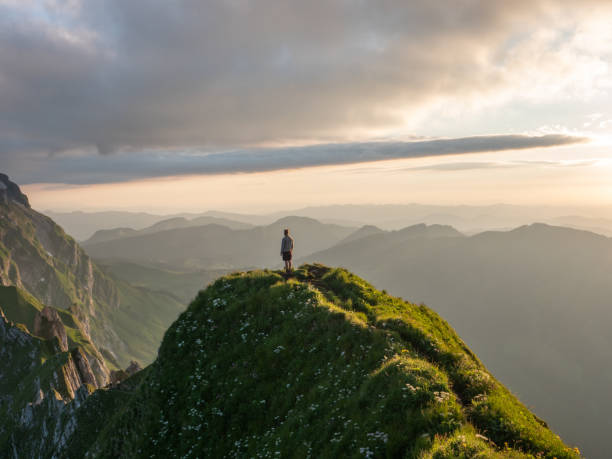 istock Distant man standing on top of mountain overlooking ridge at sunset 1266780863