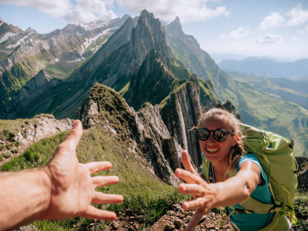 istock Hiker helping teammate to climb rock on mountain ridge 1266780917
