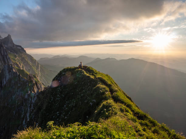 istock Distant man standing on top of mountain overlooking ridge at sunset 1266780978