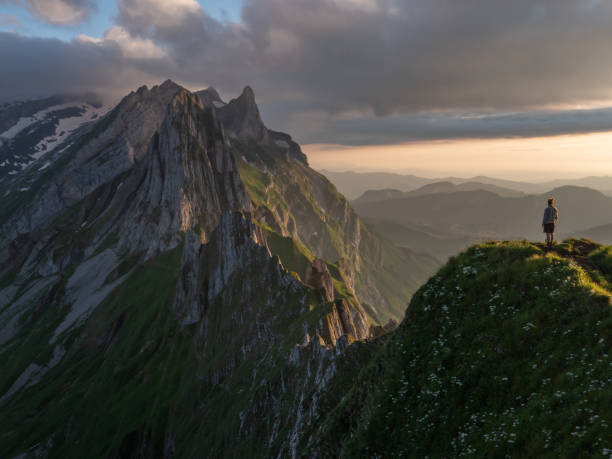 istock Distant man standing on top of mountain overlooking ridge at sunset 1266781004
